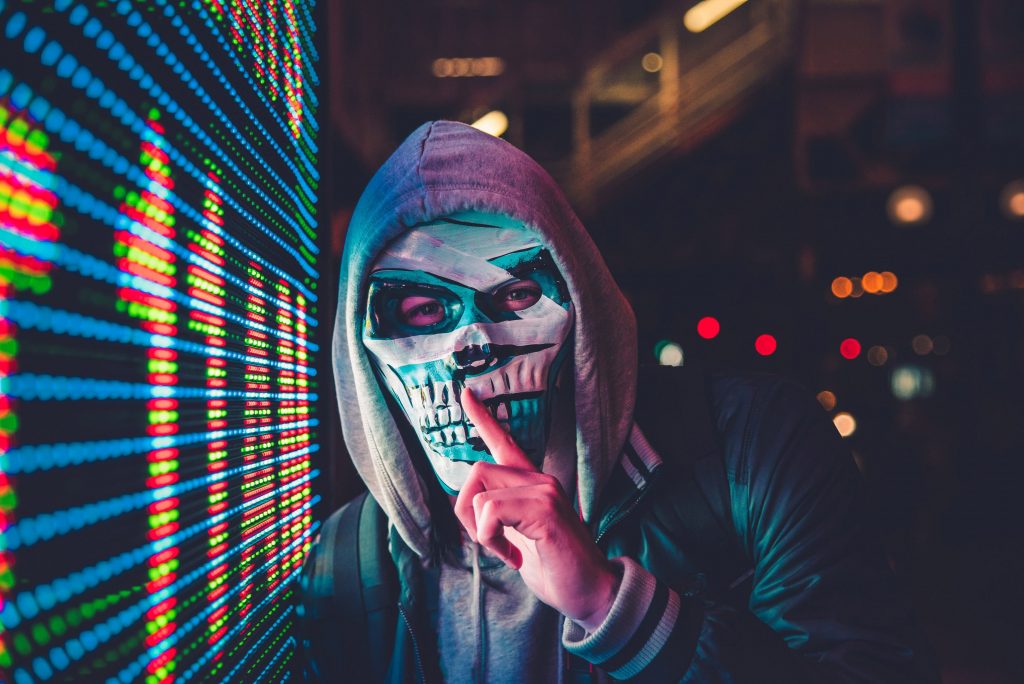 Masked person standing next to screen.