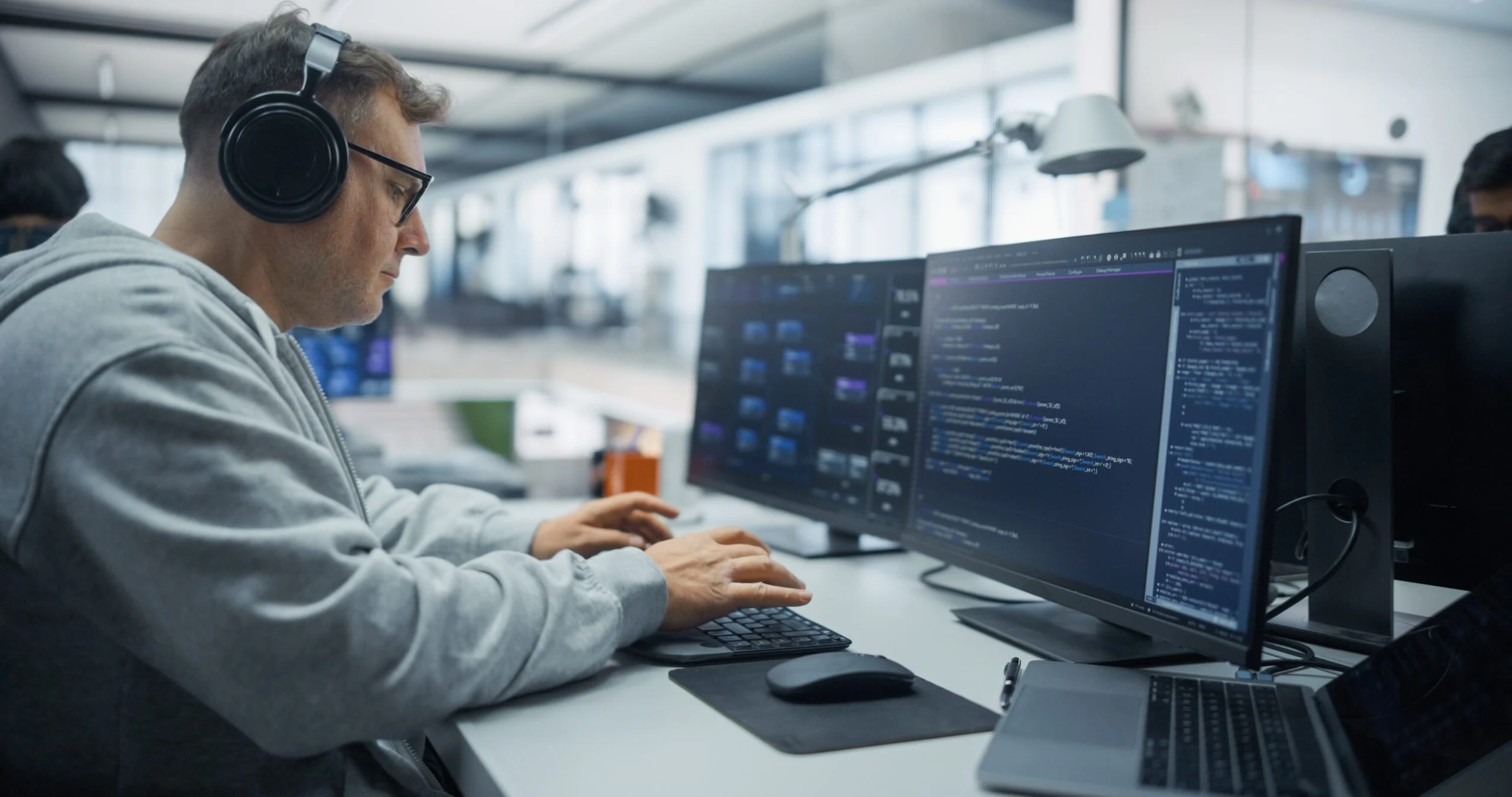 Developer prototyping MongoDB queries on dual monitors in a modern office workspace
