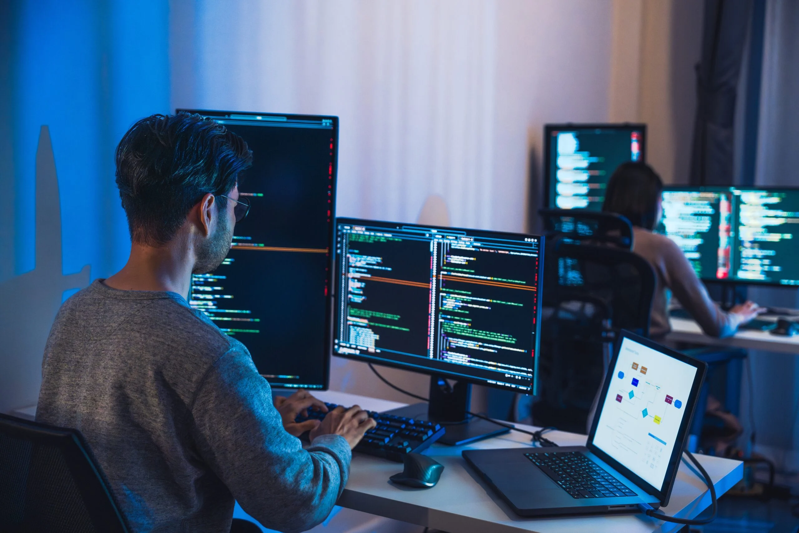 Software engineers working at multiple monitors reviewing code and data pipelines to support data readiness for AI.
