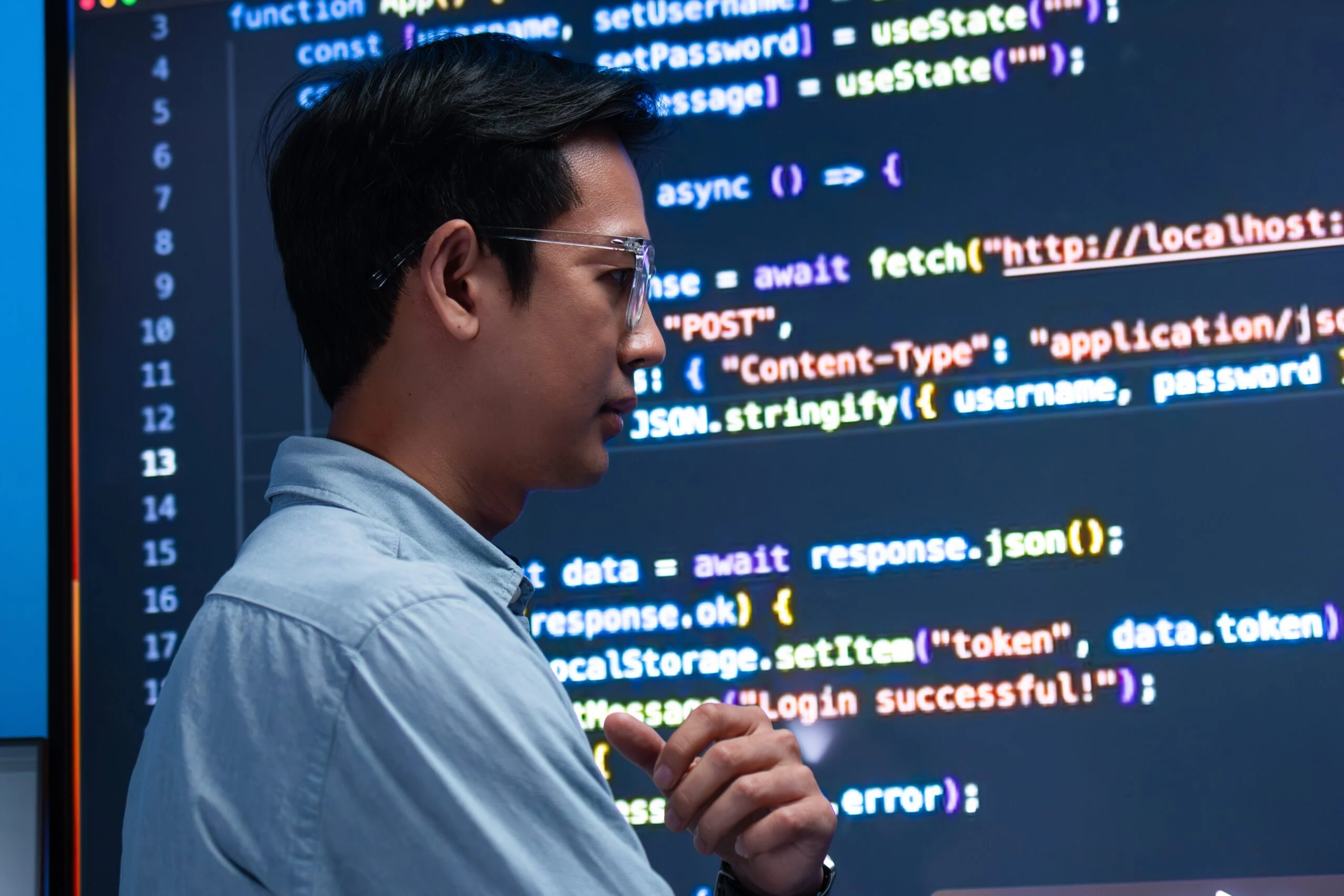 Developer reviewing code for a login authentication flow on a large monitor, illustrating backend application logic relevant to AI agent data access.
